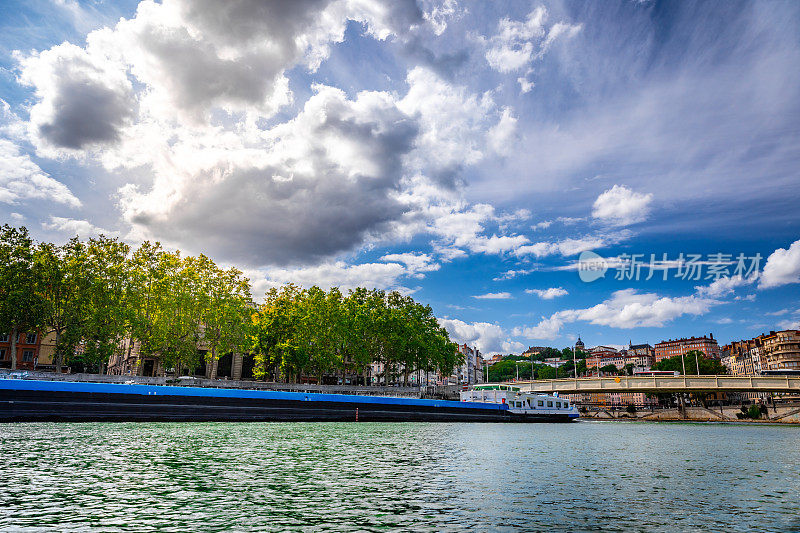 一艘大型驳船，在法国里昂市的Saone河上进行货运，背景是Croix Rousse区